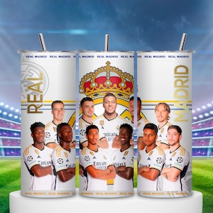 Puede incluir: Vaso blanco con el equipo del Real Madrid. El diseño incluye el logo del equipo, una corona dorada y las palabras "REAL" y "MADRID". El fondo muestra un estadio con luces brillantes y un campo verde.
