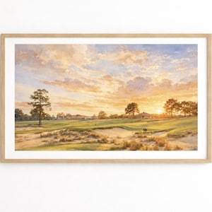 May include: A framed landscape painting of a golf course at sunset. The sky is filled with warm colours, and the course features green grass, sand traps, and trees. The artwork is displayed on a white wall.