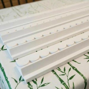 May include: A set of three white wooden wall shelves, each featuring a distinct front edge design. One shelf has a straight edge, one has a small scalloped edge, and the third has a larger scalloped edge, all finished in a matte white paint.