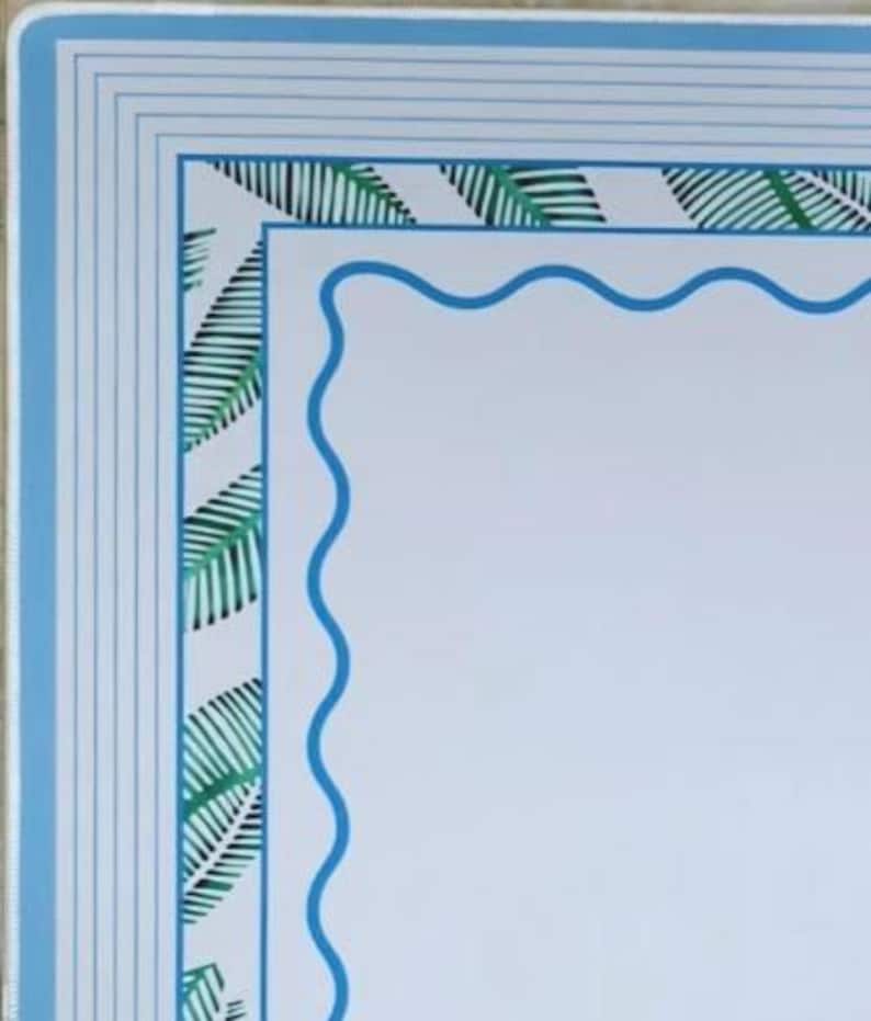 May include: A rectangular border design featuring a white center enclosed by a blue wavy line. The outer frame consists of a green palm leaf pattern on a white background, finished with multiple thin blue lines along the outermost edge.