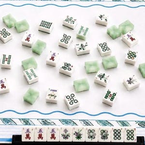 coastal inspired mahjong mat featuring custom ivory stitching, blue and while pinstripe boarder,  palm leaves and a bold coastal blue wavy line- all to lead you to a clean center for game night