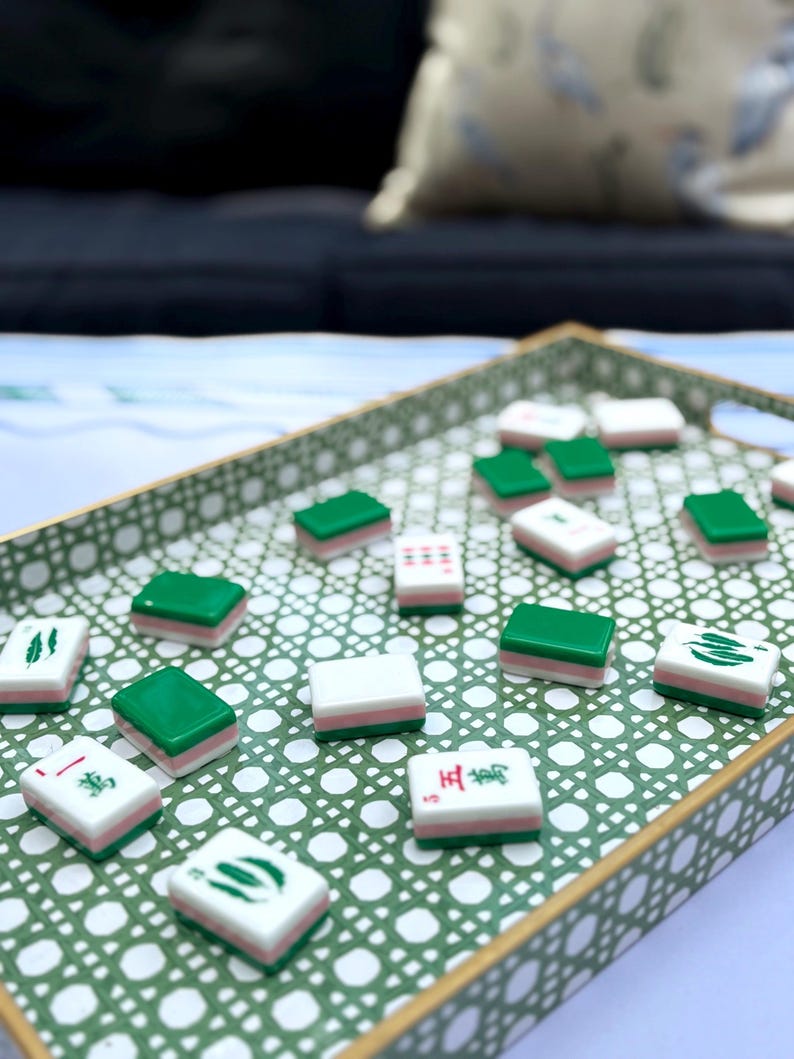 A collection of green and pink mahjong tiles with various symbols scattered across a green and white patterned tray.