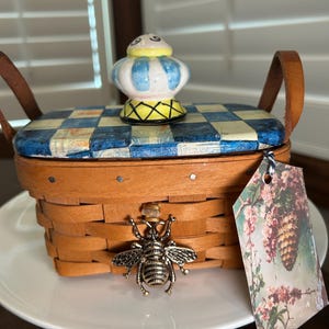 May include: A white ceramic mug with a black handle and the text "But First, Coffee" in a bold, black font. The mug is set against a blurred background, highlighting its clean design.