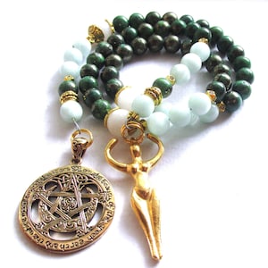 May include: A green and white beaded necklace with a gold pendant featuring a pentagram and the text "Earth and Air, Fire and Water, the stars I claim, the beauty of the green". A second gold pendant is a stylized female figure.
