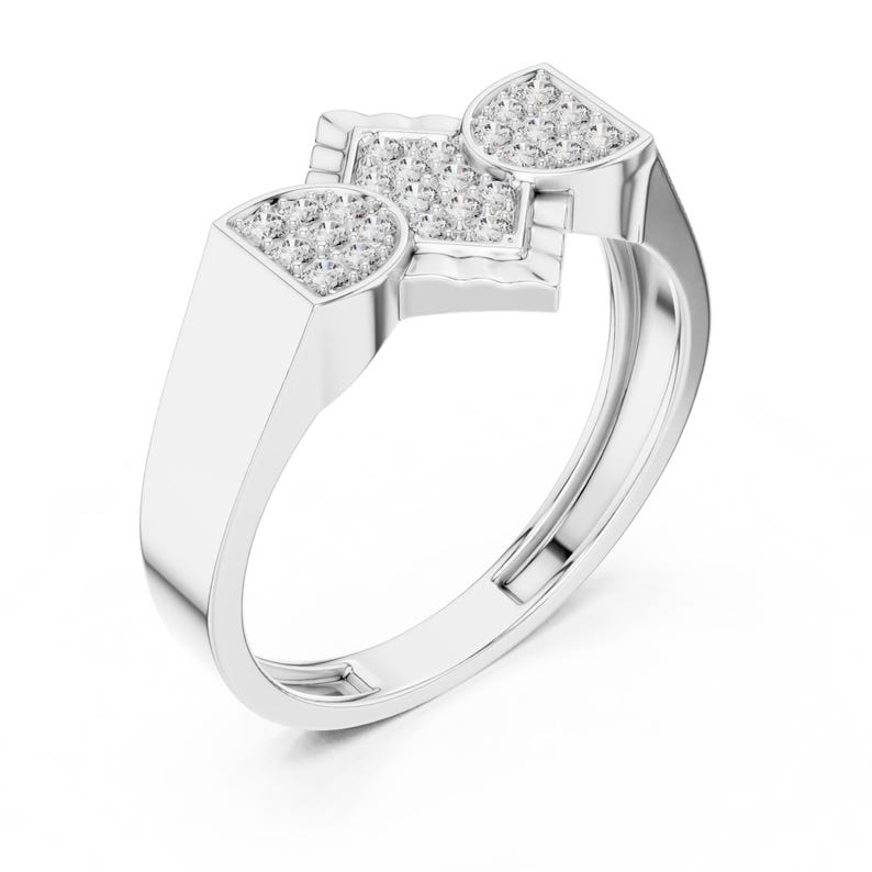 May include: A silver ring with a geometric design. The ring features three sections, each with small, sparkling stones. The band is smooth and polished, creating a modern and elegant look. The ring is set against a white background.