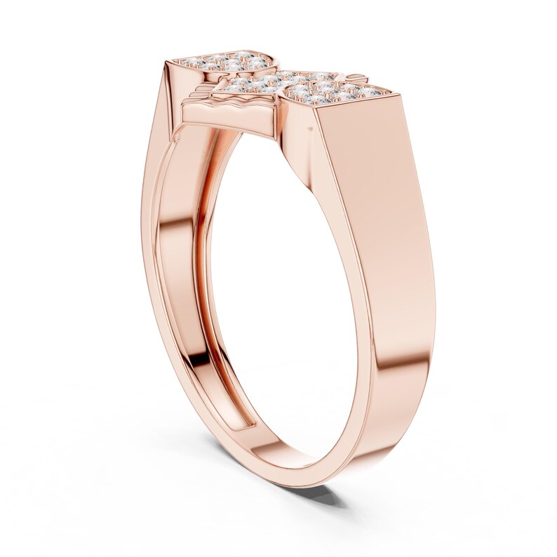 May include: Rose gold ring with a geometric design. The ring features a rectangular top with a cluster of small, clear gemstones. The band is smooth and polished, creating a modern and elegant look.