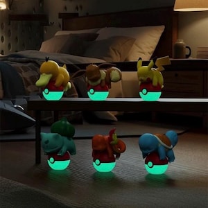 Può includere: Sei luci notturne a tema personaggi, ognuna con un personaggio diverso appoggiato su una base rossa e bianca con una luce verde brillante. I personaggi includono un'anatra gialla, una volpe marrone e Pikachu giallo.
