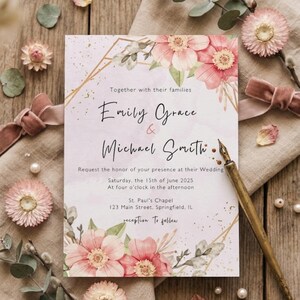 May include: Wedding invitation with floral watercolor design. The invitation features the names "Emily Grace & Michael Smith" and event details. Pink and gold accents with a vintage pen and floral embellishments.