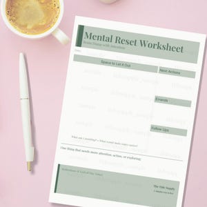 May include: A white worksheet titled "Mental Reset Worksheet" with sections for notes, next actions, and errands. A cup of coffee and a pen are next to the worksheet on a pink surface.