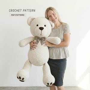Puede incluir: Un gran oso de peluche de ganchillo de color crema con una pajarita marrón. El oso tiene una superficie texturizada y ojos y nariz de color marrón oscuro. El texto "CROCHET PATTERN PDF PATTERN" está en la esquina superior izquierda.