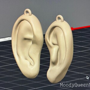 May include: A pair of beige 3D printed earrings shaped like human ears.