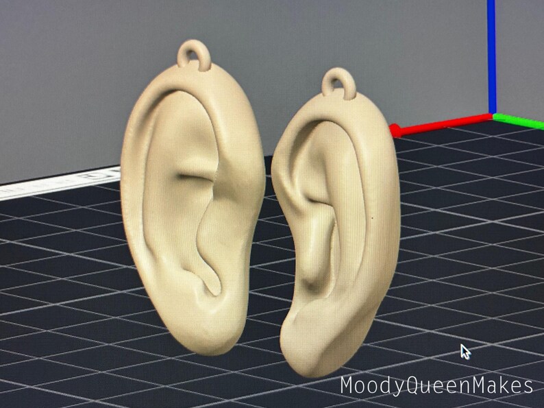 May include: A pair of beige 3D printed earrings shaped like human ears.