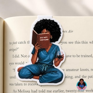 May include: A die-cut bookmark featuring an illustration of a person with dark curly hair wearing blue scrubs, sitting cross-legged while holding a brown book with the text DO NOT DISTURB on the cover and a glass of red wine in the other hand.