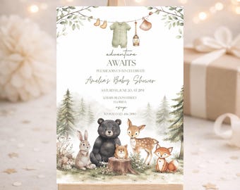 May include: A baby shower invitation on a wooden easel. The invitation features the text "adventure AWAITS" and details for Amelia's Baby Shower. The design includes watercolor illustrations of woodland animals and greenery.