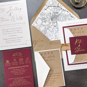 May include: A wedding invitation suite with a burgundy and gold color scheme. The invitation features the couple's names, "Kate Zwilling & Steven Walls", and the date of their wedding, "Friday, the tenth of December Two thousand twenty one". The invitation also includes the location of the wedding, "Cork Factory Hotel, 480 New Holland Avenue, Lancaster, Pennsylvania".