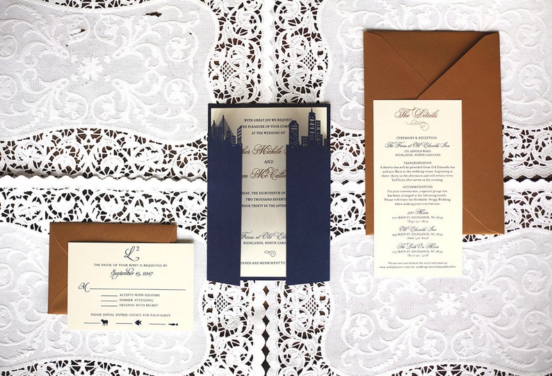Puede incluir: Un conjunto de invitaciones de boda con un esquema de color azul marino y dorado. Las invitaciones presentan un dise&ntilde;o de ciudad y el texto "Con gran alegr&iacute;a les solicitamos el placer de su compa&ntilde;&iacute;a en la boda de..." y "Los detalles".