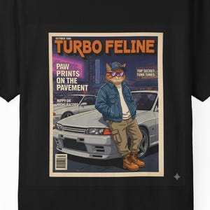 May include: Black t-shirt featuring a magazine-style graphic with the text "TURBO FELINE." The graphic depicts a cat in sunglasses and a jacket leaning against a car. Additional text includes "PAW PRINTS ON THE PAVEMENT" and "TOP SECRET TUNA TUNES."