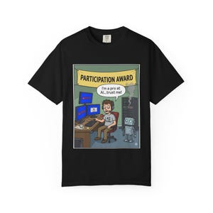 May include: Black t-shirt with a cartoon illustration of a person at a computer, with the words "PARTICIPATION AWARD" above. The image includes the text "I'm a pro at AI...trust me!" and "AI GURU".