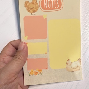 May include: A notepad with a farm theme, featuring illustrations of chickens and chicks. The notepad has a light beige background with a large yellow section and several smaller peach-colored sections. The word "NOTES" is in an oval at the top.