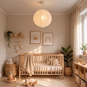 May include: A light and airy nursery with a wooden crib, a round paper lantern, and framed art prints. The room features a neutral color palette with a woven basket, a rug, and a wooden toy. A cozy and inviting space for a baby.