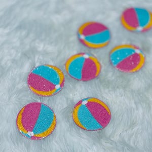 May include: Six circular patches featuring a beach ball design with alternating segments of bright pink, turquoise blue, and yellow. Each patch has a textured, beaded surface with a small white circle at the center point where the segments meet.