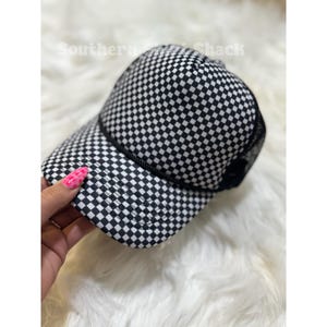 May include: Black and white checkered baseball cap with a mesh back. The cap features a classic six-panel design and a curved brim. The text "Southern Shack" is visible on the top of the cap.