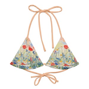 May include: A bikini top featuring a watercolor-style floral print with red poppies, white daisies, and blue cornflowers on a light background. The garment has solid peach-colored fabric ties at the neck and back for an adjustable fit.