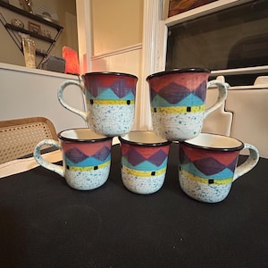 May include: Five ceramic mugs with a speckled white base and colorful geometric designs. Each mug features a red rim, a purple and turquoise pattern, and a yellow stripe. The mugs have a handle and a black rim.
