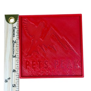 May include: A red square patch with the text "PETS PEAK SUPPLY CO" and a mountain and bird design. The patch measures approximately 3 inches by 3 inches.