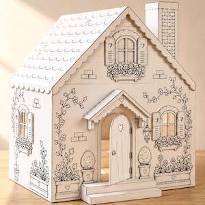 May include: A white cardboard playhouse featuring black line art illustrations of flowers, climbing vines, windows with shutters, a chimney, and a front door with a heart cutout. The structure includes a roof with scalloped edges and steps.