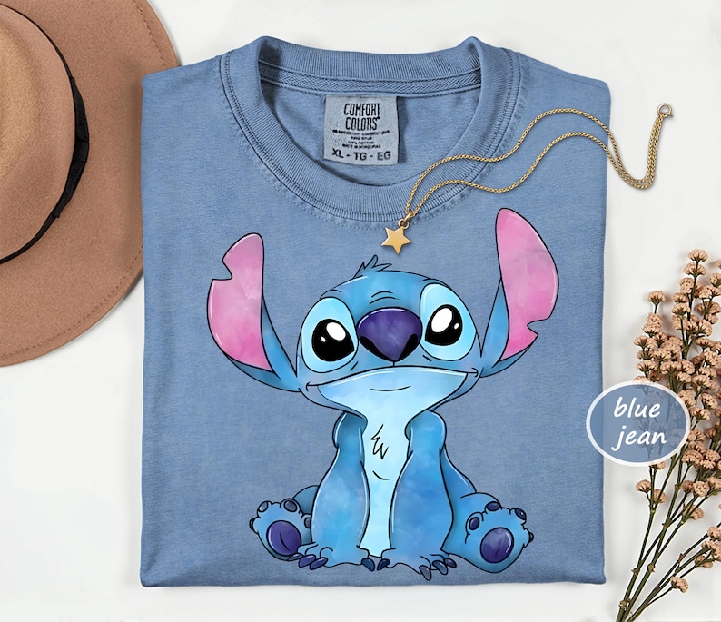 A blue t-shirt with a cartoon character printed on it, along with a necklace and a hat.