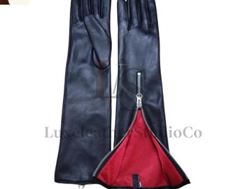 May include: A pair of long black leather gloves with a red interior. One glove features a silver zipper that runs from the wrist to the fingertips. The gloves are from LuxeLeatherStudioCo.