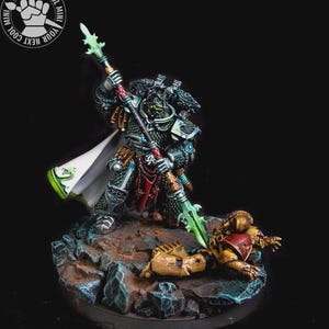 Puede incluir: Figura en miniatura detallada de un guerrero con armadura verde oscuro y plateada, sosteniendo una lanza con una hoja verde. La figura está de pie sobre un oponente caído sobre una base rocosa. La figura tiene una capa blanca con detalles verdes. El texto "YOUR NEXT COOL MINI" está en la esquina superior izquierda.