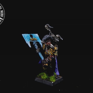 以下が含まれることがあります： 大きな青い斧を持ったファンタジーの戦士のミニチュアフィギュア。このフィギュアは、骸骨のような顔をしており、紫色のアクセントが付いた鎧を着用しています。ベースは緑色で、フィギュアは黒い背景に配置されています。「YOUR NEXT COOL MINI」というテキスト。