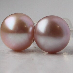 May include: A pair of pearl earrings with a soft pink hue. The pearls are round and have a smooth, glossy finish.