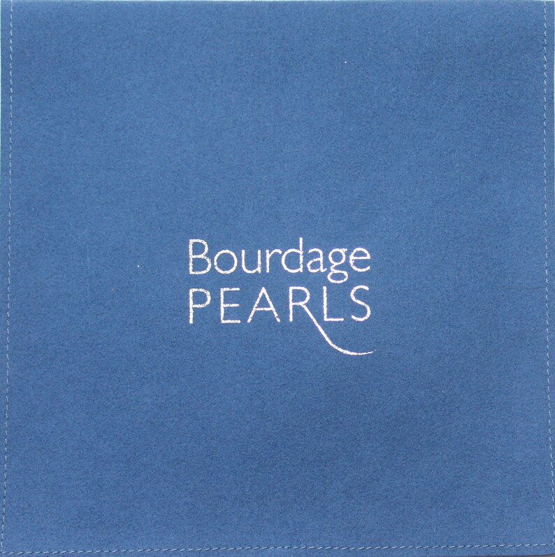 Pu&ograve; includere: Una bustina quadrata in tessuto blu con cuciture visibili lungo i bordi. Il testo Bourdage PEARLS &egrave; stampato in bianco al centro, con una linea stilizzata che si estende dalla lettera L, creando una presentazione pulita e semplice.