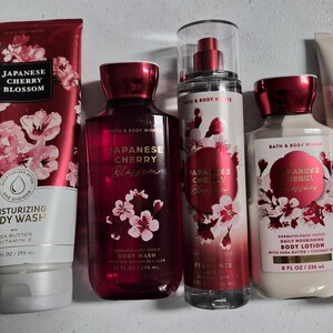 以下が含まれることがあります： Bath & Body WorksのJapanese Cherry Blossomシリーズのボディケア製品5点セット。ボディウォッシュのチューブとボトル、フレグランスミスト、ボディローションのボトル、ボディクリームのチューブが含まれており、すべて桜の花のデザインが施されています。