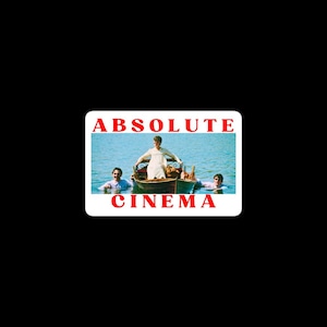 以下が含まれることがあります： 赤い文字で「ABSOLUTE CINEMA」と書かれた長方形のステッカー。ステッカーには、湖でボートに乗っている人々のヴィンテージ画像が使用されています。人々は明るい色の服を着ています。
