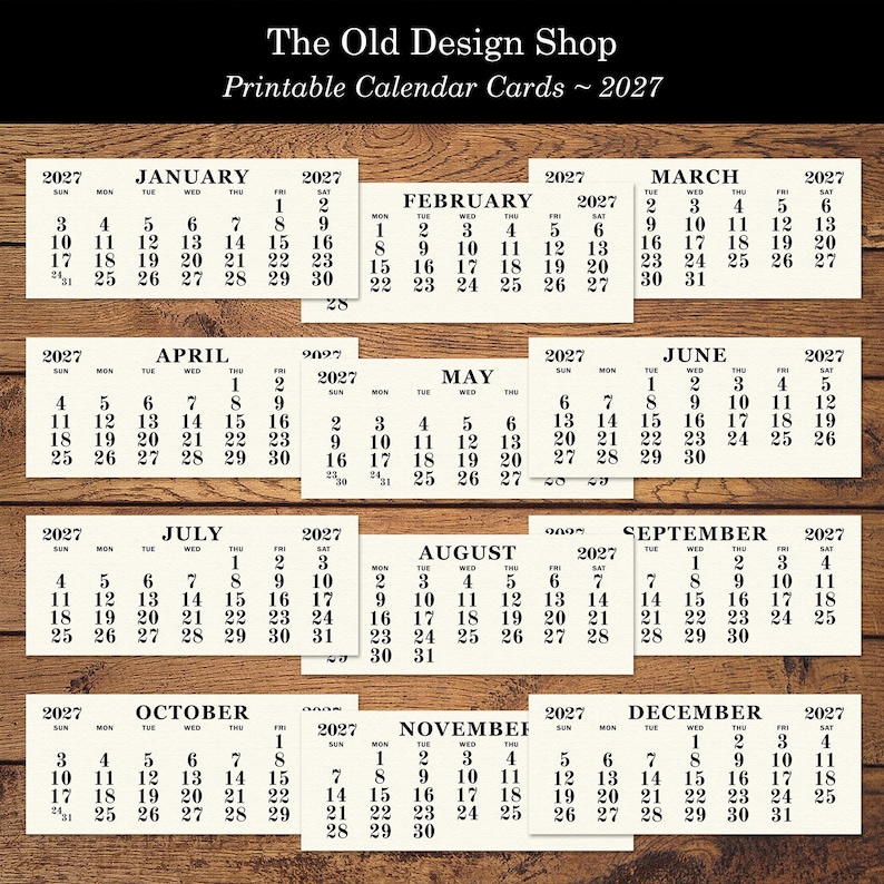 May include: Printable calendar cards for 2027, featuring each month with dates and days of the week. The Old Design Shop logo is at the top. The calendars are arranged on a wooden surface.