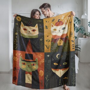 Könnte beinhalten: Eine rechteckige Wohndecke mit einem viergeteilten Rasterdesign. Jedes Feld zeigt eine stilisierte Katze in formeller Kleidung, darunter Zylinder, Fliegen und Westen, vor herbstlich gestalteten Hintergründen mit Blättern und Himmelsmotiven.