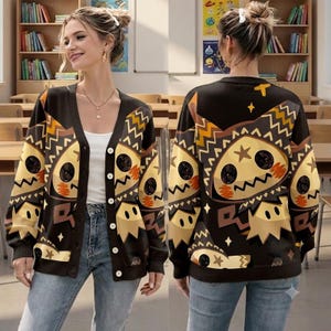 Peut inclure: Un cardigan noir boutonné avec un motif graphique répétitif représentant une créature jaune et marron à la bouche dentelée et aux accents en forme d'étoile. Le vêtement en tricot a des manches longues, un col en V et une fermeture boutonnée.