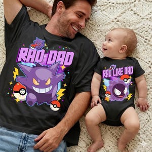 May include: Black t-shirt with the text "RAD DAD" and a purple cartoon character with a wide grin, lightning bolts, and Pokeballs. A baby in a black onesie with the text "RAD LIKE DAD" and a similar cartoon character.