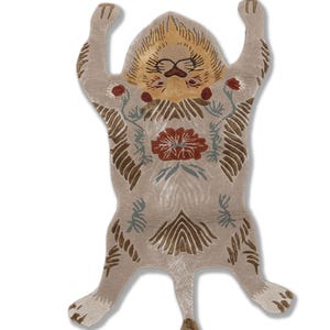 May include: A beige rug in the shape of a lion with its arms raised. The rug features a lion's face with a yellow mane, a red flower, and floral and geometric patterns. The rug is from Velmora Livings.