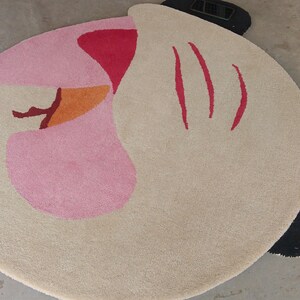 Detailed close-up of the plush charcoal black wing tips extending past the circular boundary of the abstract rug.