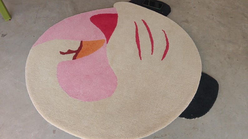 Detailed close-up of the plush charcoal black wing tips extending past the circular boundary of the abstract rug.