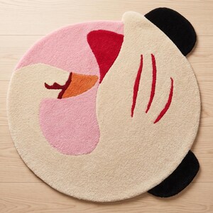 Full overhead shot of an irregular shaped rug featuring a stylized whimsical pink and cream swan rug design, a premium Wollteppich.