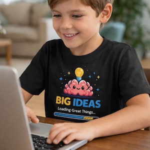 Op de afbeelding: Een witte keramische mok met een zwart handvat en de tekst "But First, Coffee" in een vetgedrukte, zwarte letter. De mok is gevuld met een donkere vloeistof, waarschijnlijk koffie, en staat op een lichtgekleurd oppervlak.