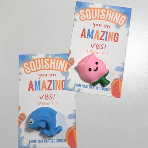 May include: Two cards with the text "SQUISHING you an AMAZING VBS! 1 Peter 5:7" and "FROM FIRST BAPTIST CHURCH". One card has a pink peach-shaped toy, the other has a blue dolphin-shaped toy. Both cards have orange and blue accents.