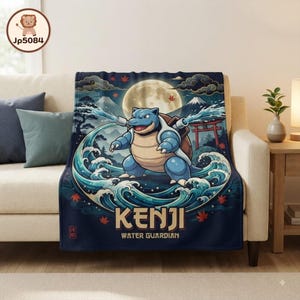 May include: A dark blue throw blanket featuring a central illustration of a blue turtle-like creature spraying water from cannons on its back. The design includes a full moon, mountains, a red torii gate, and the text KENJI WATER GUARDIAN.