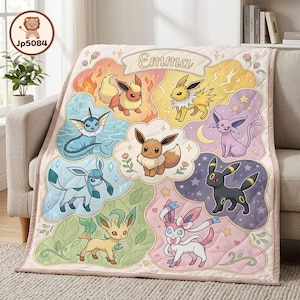 May include: A quilted throw blanket featuring a central Eevee surrounded by its evolutions including Flareon, Jolteon, Vaporeon, Espeon, Umbreon, Glaceon, Leafeon, and Sylveon. The top banner displays the name Emma in a cursive script font.